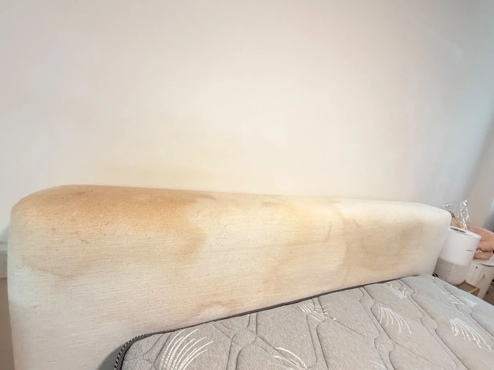 Upholstered headboard before cleaning — visible staining and discolouration