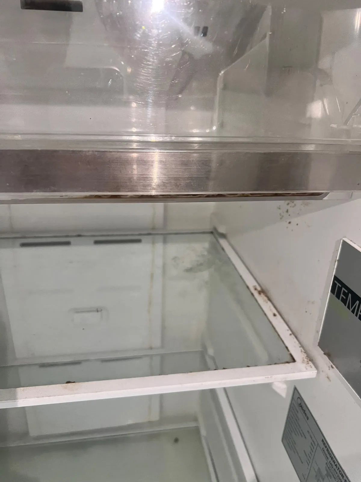 Post-tenancy before cleaning โ refrigerator interior with grime and residue
