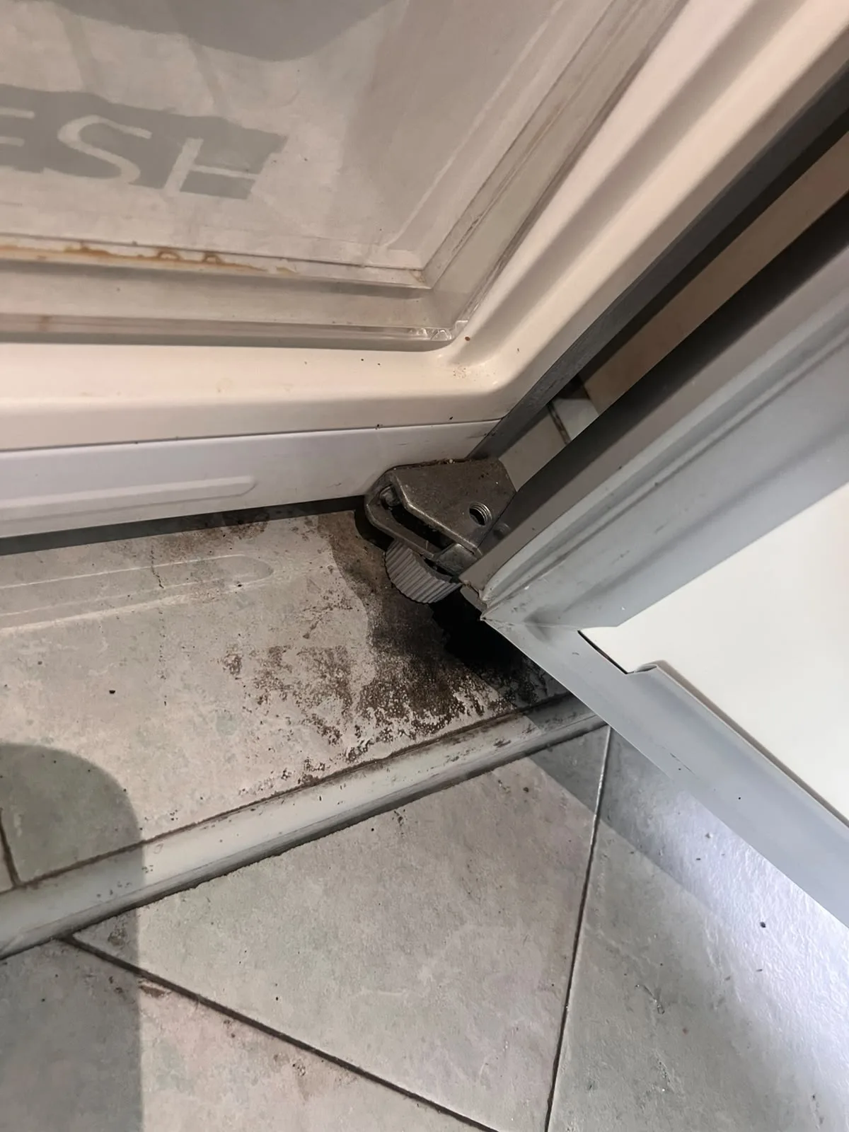 Post-tenancy before cleaning โ grime and debris in floor corner beside refrigerator