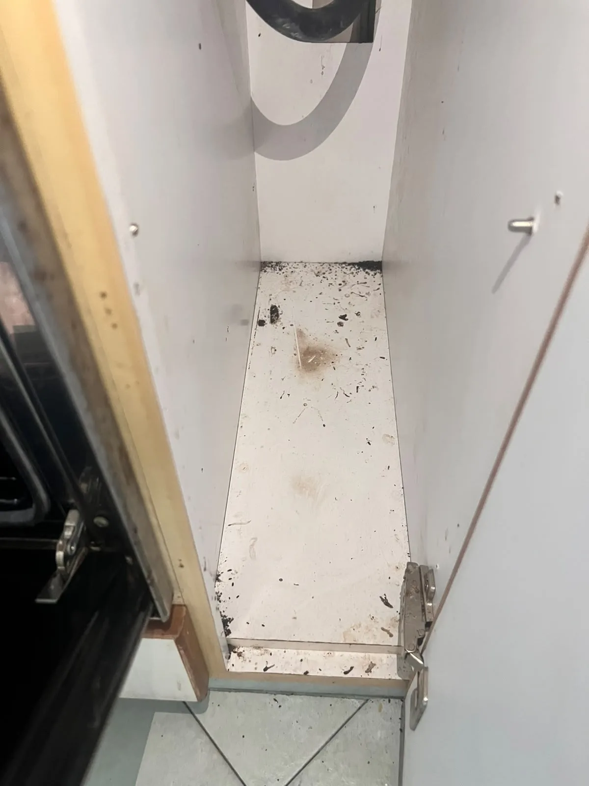 Post-tenancy before cleaning โ narrow kitchen cabinet with cockroach droppings and grime